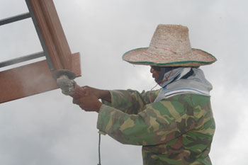 A Burmese worker uses a power tool to finish roof trim on a new house.