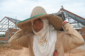 A Burmese construction workers carries roof tiles at a Chiang Mai construction site.