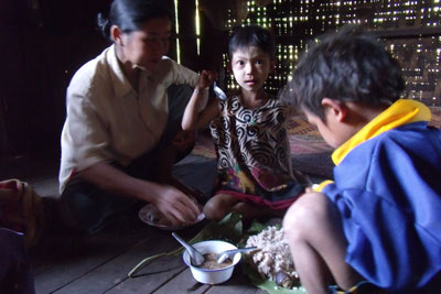 Daw Kye Mae  and two of her children are eating.