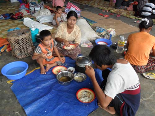 A Kachin family is eating a meal in a crowded IDP camp in Laiza