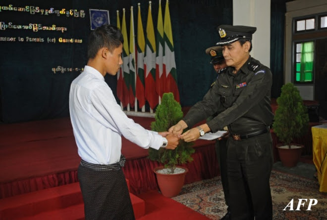 A discharged Myanmar child soldier (L) receives his new national registration card from a Myanmar Immigration official during a ceremony discharging a group of children and young people back to their parents and guardians on January 18, 2014. AFP PHOTO / SOE THAN WIN