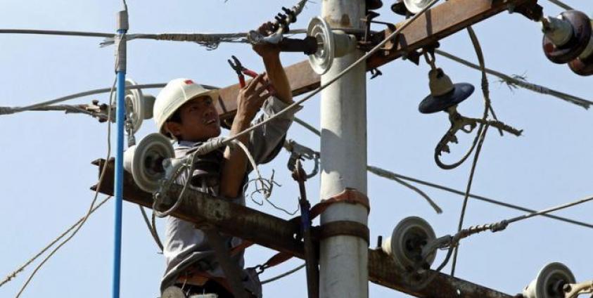 A labourer works on an electric power pole to modify and maintain the high voltage power cables in Mandalay, Myanmar. Photo: EPA