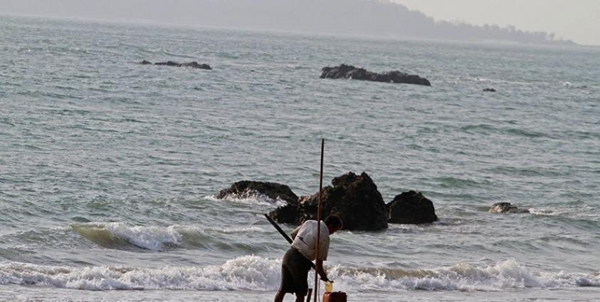 A Rakhine ethnic man collects oil on the shore of Kyauk Phyu, Rakhine state, western Myanmar. Photo: EPA