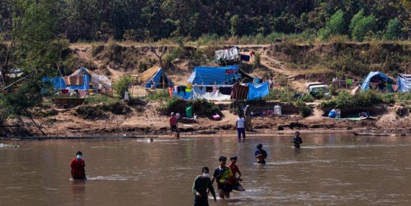 This photo taken on January 15, 2022 shows Myanmar refugees, who fled a surge in violence as the military cracks down on rebel groups, walking across the river on the Thai border as pictured from Thailand's Mae Sot district. Photo: AFP