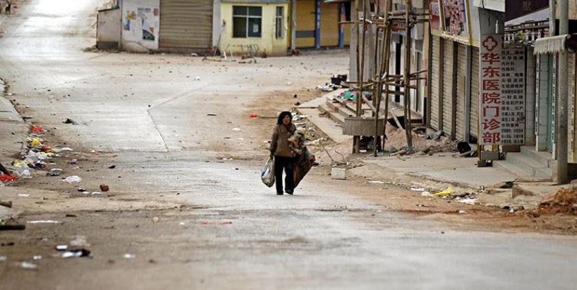 (File) A woman walks along a deserted road in self-administered Kokang capital Laukkai, northern Shan State, Myanmar, 16 February 2015. Photo: Lynn Bo Bo/EPA