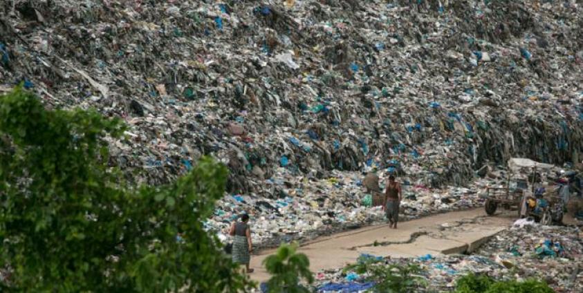 People walk past a garbage dump on the outskirts of Yangon on June 5, 2019. Photo: Sai Aung Main/AFP