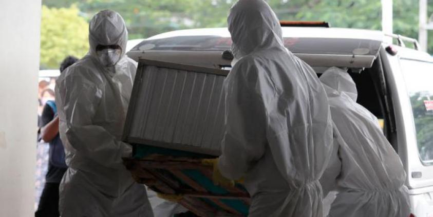 Members of Yangon Free Funeral Service Society (FFSS) wearing protective clothes carry the coffin of a person who has died from influenza A (H1N1) arrives at a cemetery in Yangon, Myanmar, 22 June 2019. Photo: Nyein Chan Naing/EPA