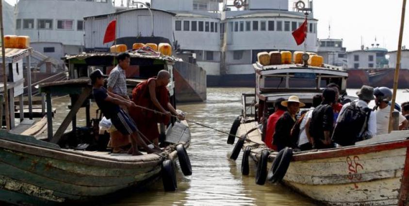 A Buddhist monk and a man pull a rope of the boat at the Chindwin river in Monywa, Sagaing Division, Myanmar. Photo: Nyein Chan Naing/EPA