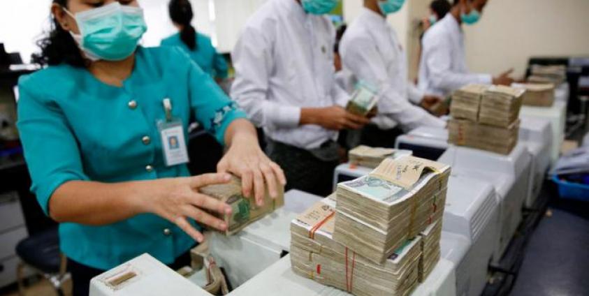 Staff members of the Asia Green Development Bank count Myanmar Kyat notes with machines at Sule branch office, in Yangon, Myanmar, 14 December 2016. Photo: EPA