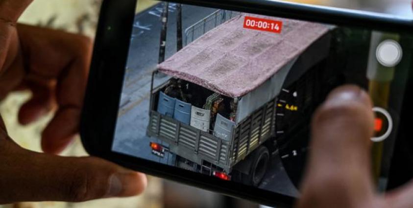 Photo: A person holds a mobile phone showing a video of soldiers looking out from a truck in Yangon. Photo: AFP