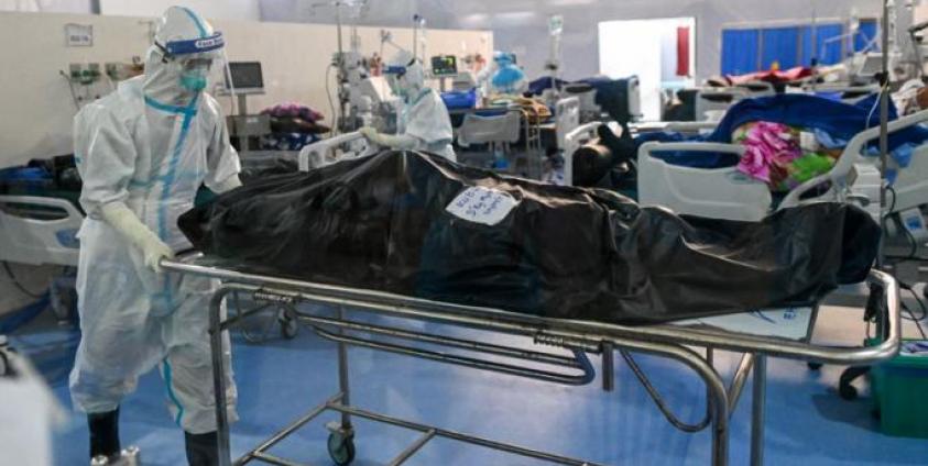 This photo taken on December 19, 2020, shows healthcare workers wearing personal protective equipment (PPE) as they prepare to transfer the body of a person who died from the Covid-19 coronavirus at the Ayeyarwady Covid Center at the Thuwana football stadium in Yangon, amid the ongoing Covid-19 coronavirus pandemic. : AFP