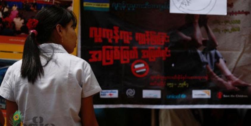 A young woman passes by a billboard campaign to human trafficking in Yangon. Photo: Mizzima