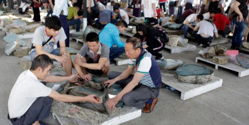 Buyers examine jade stones on sale displayed prior to an auction during the March Gems Emporium in Naypyitaw, Myanmar, 12 March 2019. The Gems Emporium runs from 11 March to 20 March 2019. Photo: Hein Htet/EPA