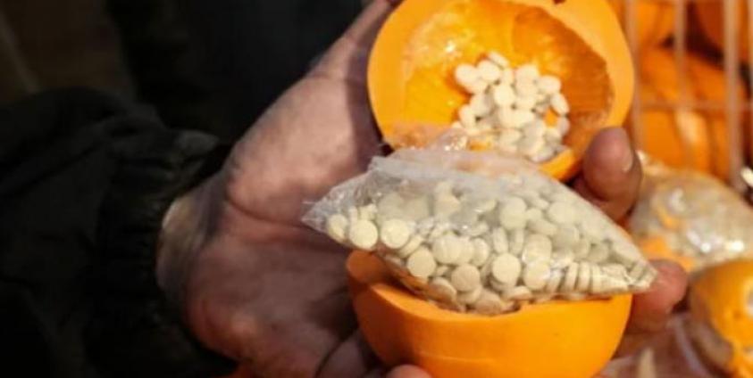 A man shows fake oranges filled with illegal drug pills. Photo: AFP