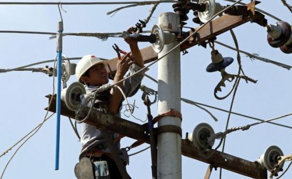 A labourer works on an electric power pole to modify and maintain the high voltage power cables in Mandalay, Myanmar. Photo: EPA