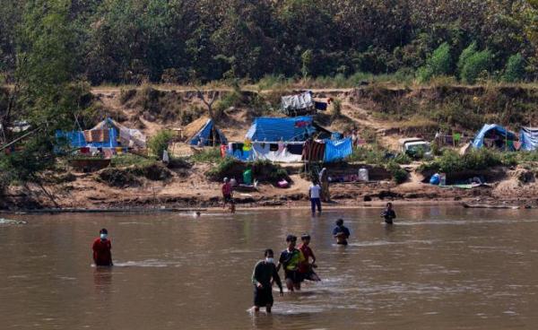 This photo taken on January 15, 2022 shows Myanmar refugees, who fled a surge in violence as the military cracks down on rebel groups, walking across the river on the Thai border as pictured from Thailand's Mae Sot district. Photo: AFP