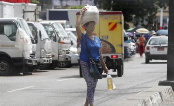 A woman carries rice and cooking oil in Yangon, Myanmar. Photo: EPA