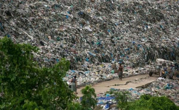 People walk past a garbage dump on the outskirts of Yangon on June 5, 2019. Photo: Sai Aung Main/AFP