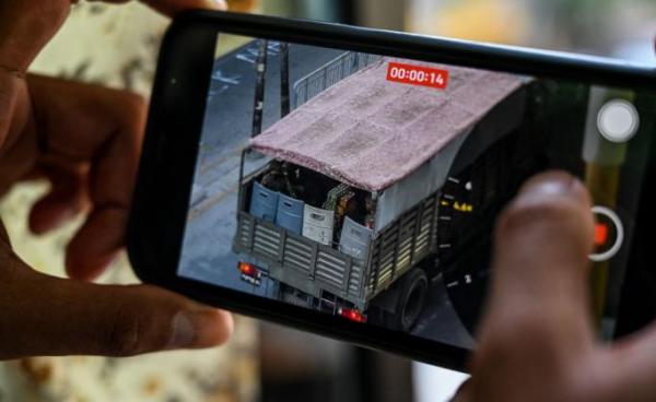 Photo: A person holds a mobile phone showing a video of soldiers looking out from a truck in Yangon. Photo: AFP