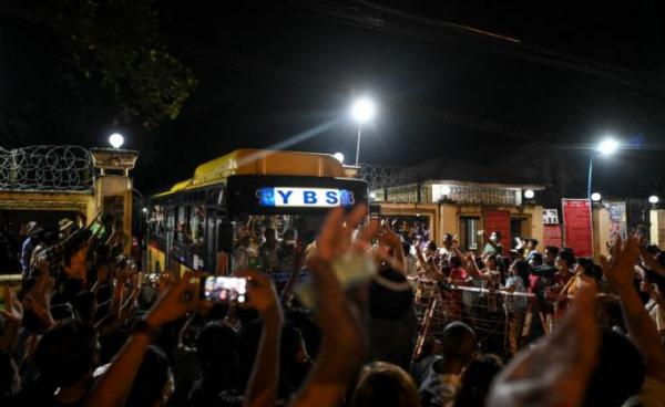 Newly-released prisoners wave from a bus as they depart the Insein Prison in Yangon on October 18, 2021, after authorities announced more than 5,000 people jailed for protesting against a February coup which ousted the civilian government would be released. AFP