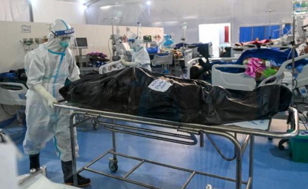 This photo taken on December 19, 2020, shows healthcare workers wearing personal protective equipment (PPE) as they prepare to transfer the body of a person who died from the Covid-19 coronavirus at the Ayeyarwady Covid Center at the Thuwana football stadium in Yangon, amid the ongoing Covid-19 coronavirus pandemic. : AFP