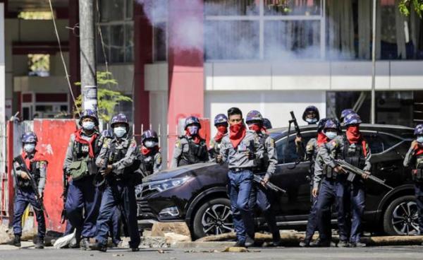 Anti-riot police officers prepare to fire tear gas as they try to disperse protesters during an anti-coup protest following the military crackdown in Yangon. Photo: EPA