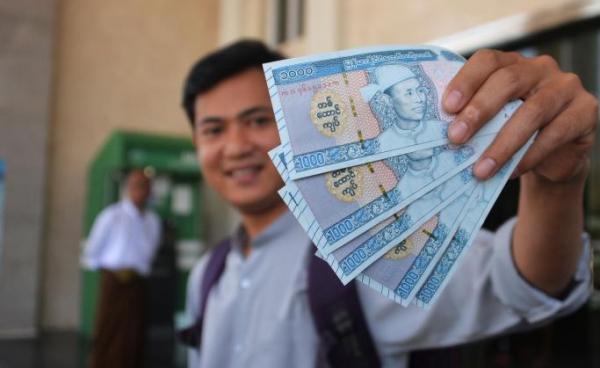 Photo: A man holds new Myanmar kyat banknotes with a portait of the late general Aung San, outside the Myanmar Economic Bank in Naypyidaw on January 7, 2020. Photo: AFP