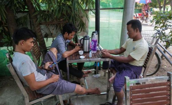 Myanmar men using their mobile phones at a teashop in Yangon. Photo: Sai Aung Main/AFP