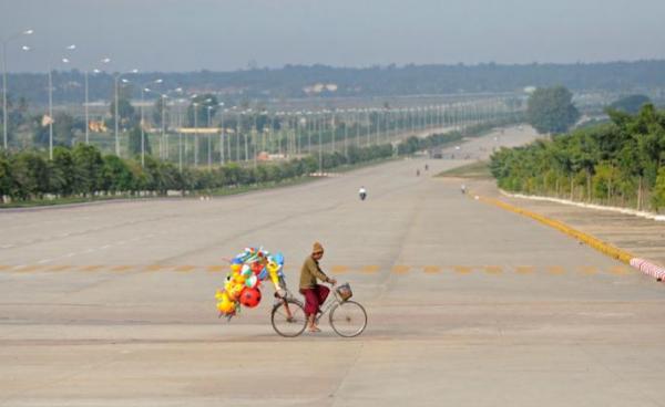 A man rides his bike across a road carrying toys to sell in Myanmar's city of Naypyidaw. Photo: EPA