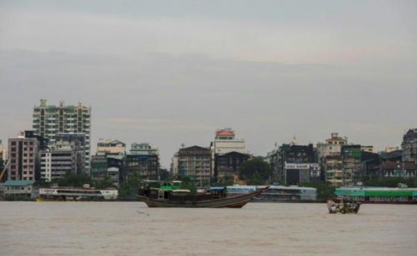 Residential and commercial buildings by the river banks as boats sail across the Yangon River. Photo: Sai Aung Main/AFP