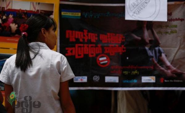 A young woman passes by a billboard campaign to human trafficking in Yangon. Photo: Mizzima