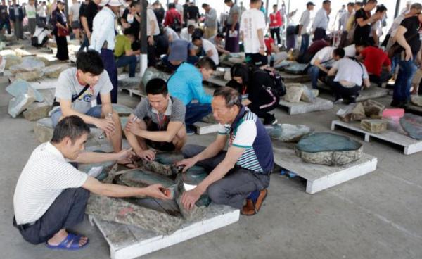 Buyers examine jade stones on sale displayed prior to an auction during the March Gems Emporium in Naypyitaw, Myanmar, 12 March 2019. The Gems Emporium runs from 11 March to 20 March 2019. Photo: Hein Htet/EPA