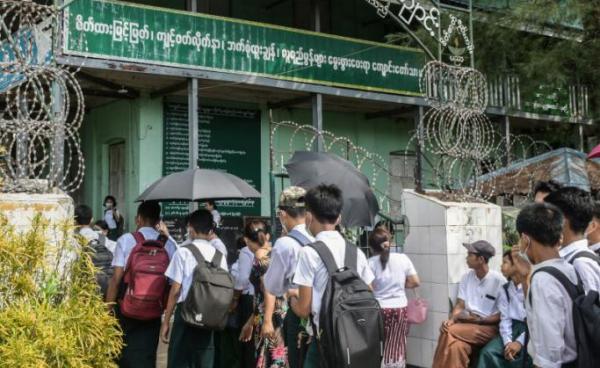 Students wait at a school entrance in Sittwe, capital of western Rakhine State on June 1, 2021. Schools in Myanmar opened on June 1 for the first time since the military seized power, but teachers and students are set to defy the junta's calls for full classrooms in a show of resistance. Photo: AFP