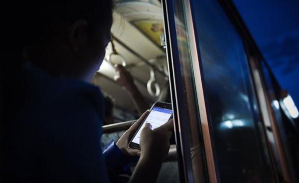 A young woman looks at her Facebook wall while she travels on a bus in Yangon. Photo: AFP 